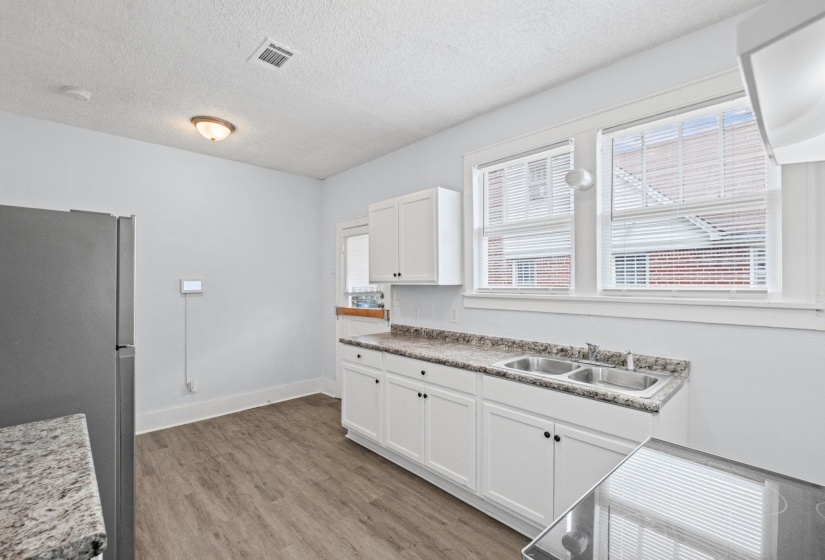 Kitchen with freestanding refrigerator, white cabinetry, light wood-style flooring, a textured ceiling, and light countertops