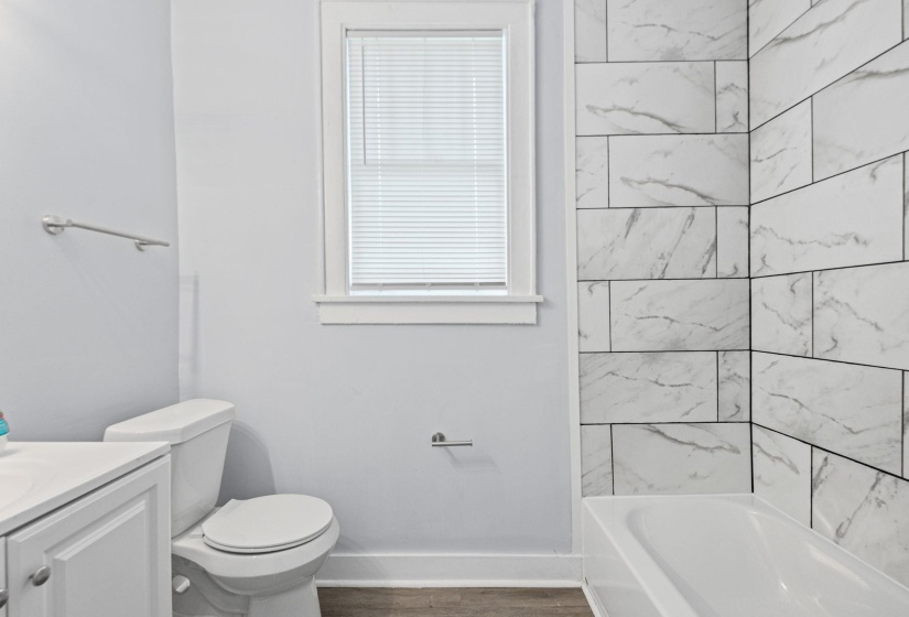 Full bath with vanity, shower / bath combination, and dark wood-style floors