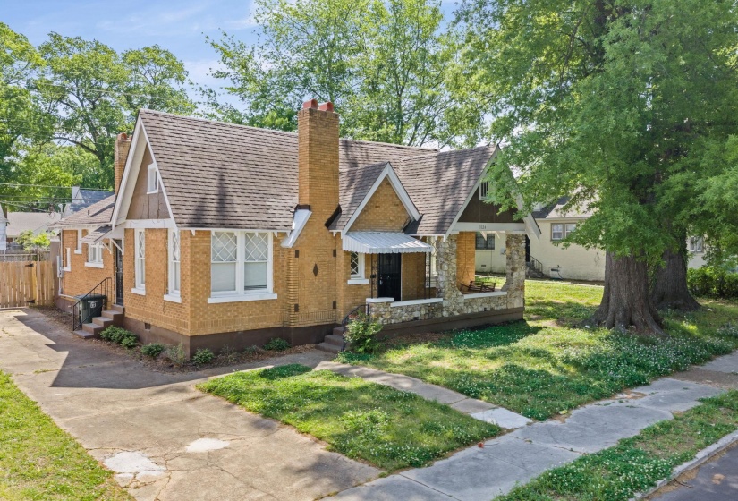 View of front of home with a chimney, a front yard, stone siding, and brick siding