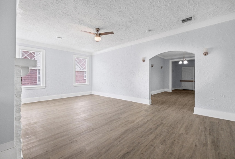 Unfurnished room with a textured wall, arched walkways, ceiling fan, crown molding, and wood finished floors