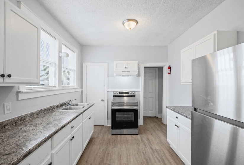 Kitchen featuring stainless steel appliances, white cabinets, light wood-style floors, and a textured ceiling