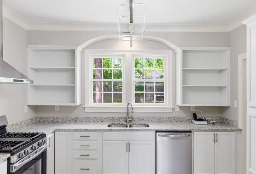 Kitchen with open shelves, stainless steel appliances, light stone countertops, white cabinetry, and ornamental molding