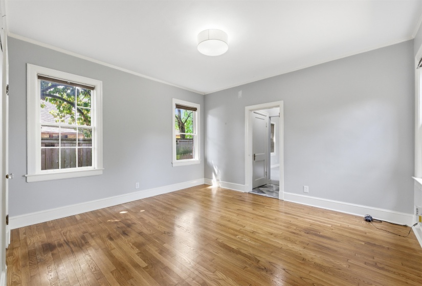 Unfurnished bedroom featuring light wood finished floors, ornamental molding, and ensuite bath