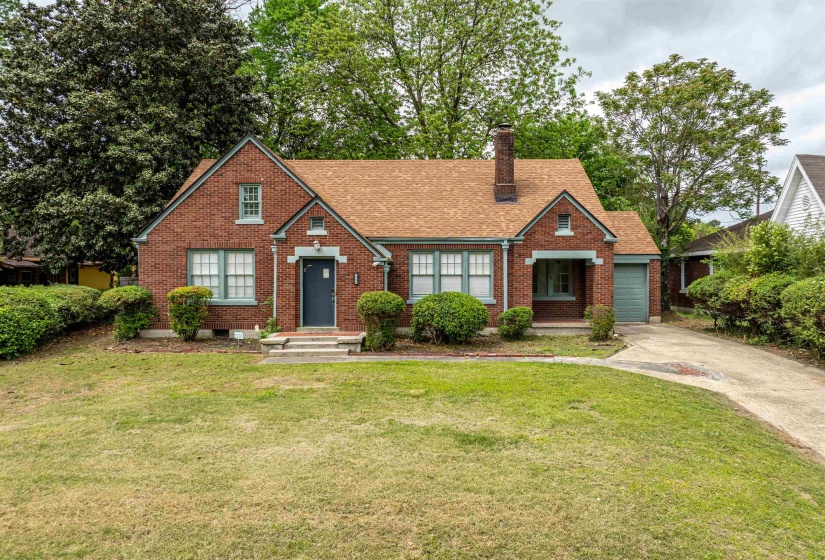 View of front of home with brick siding, a chimney, and a front yard