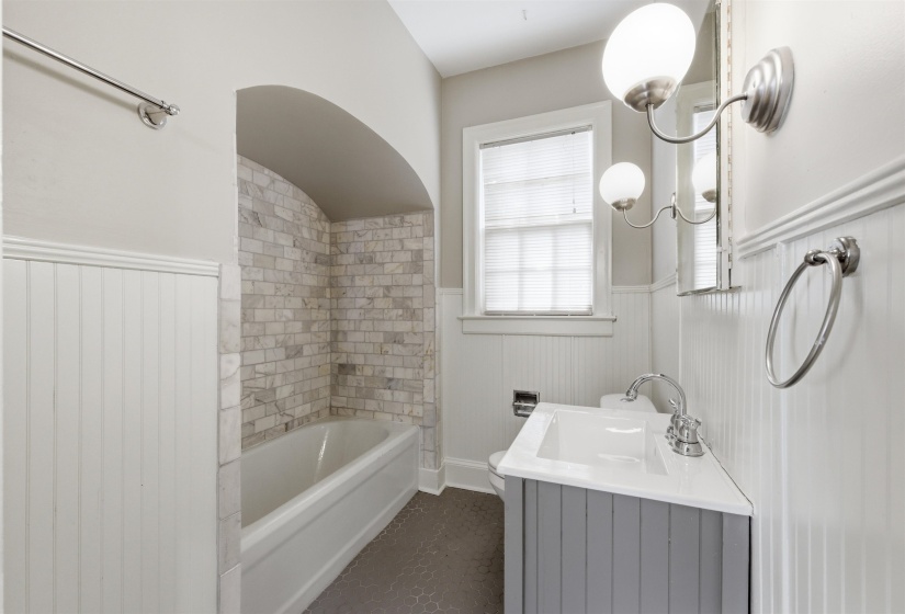 Bathroom with vanity, a wainscoted wall, and tub / shower combination