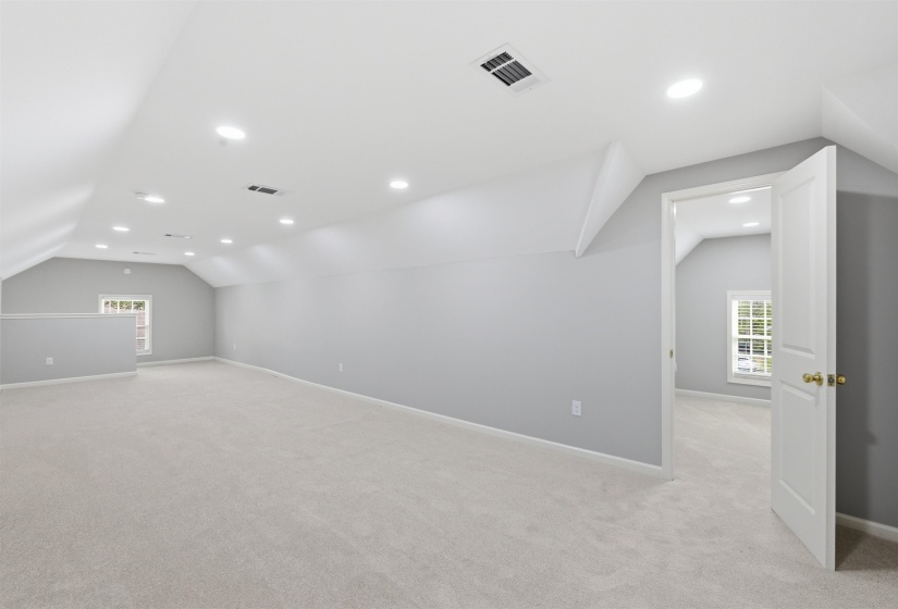 Additional living space with light carpet and recessed lighting