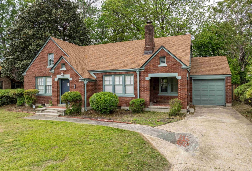 View of front facade featuring driveway, an attached garage, a chimney, brick siding, and a shingled roof