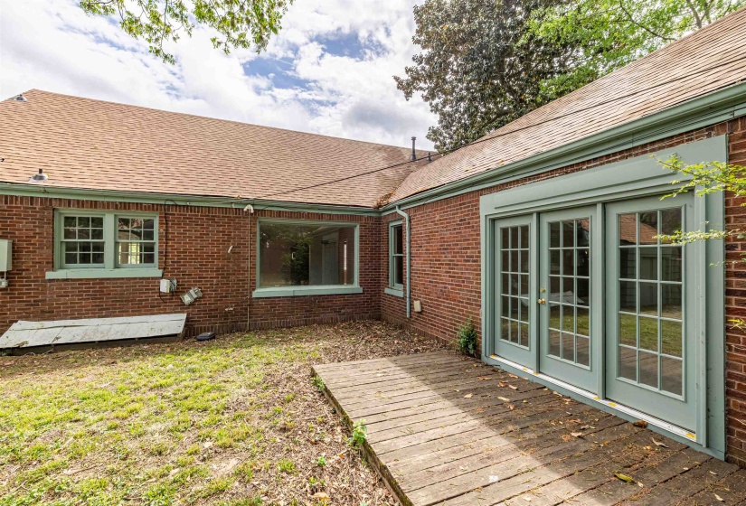 Back of house featuring brick siding, french doors, a shingled roof, and a deck
