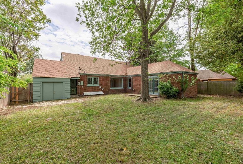 Rear view of house with a fenced backyard, brick siding, and roof with shingles