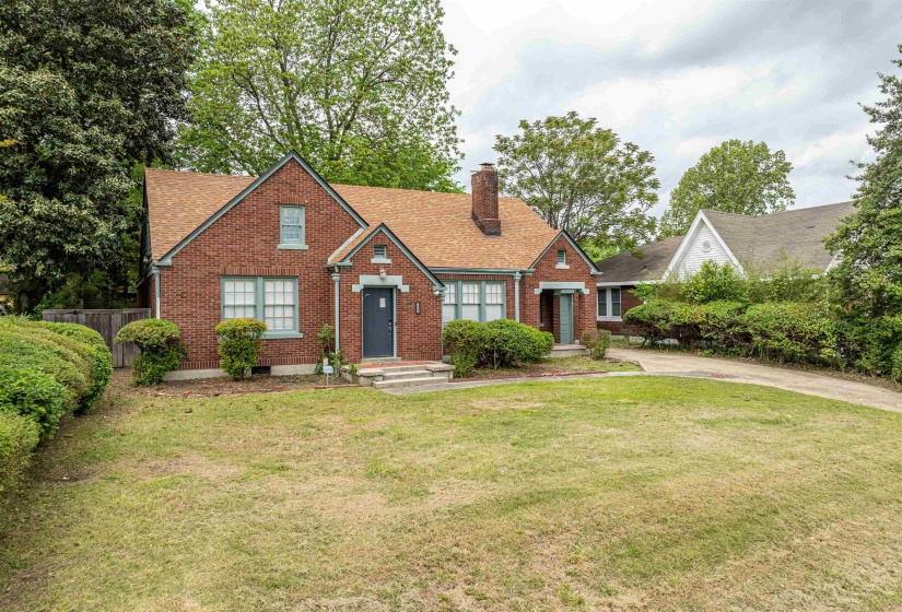 View of front of home with brick siding, a chimney, and roof with shingles