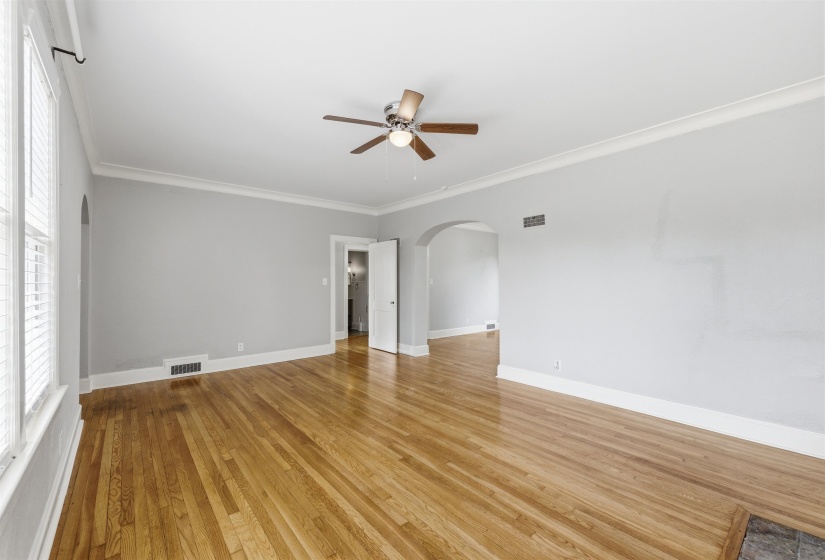 Unfurnished room featuring arched walkways, crown molding, light wood finished floors, and ceiling fan