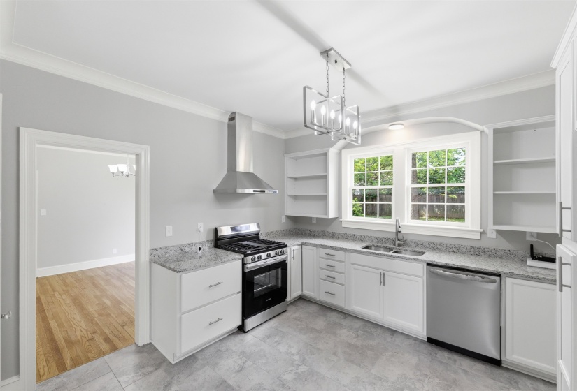 Kitchen featuring open shelves, suspended lighting, stainless steel appliances, white cabinetry, and light stone counters