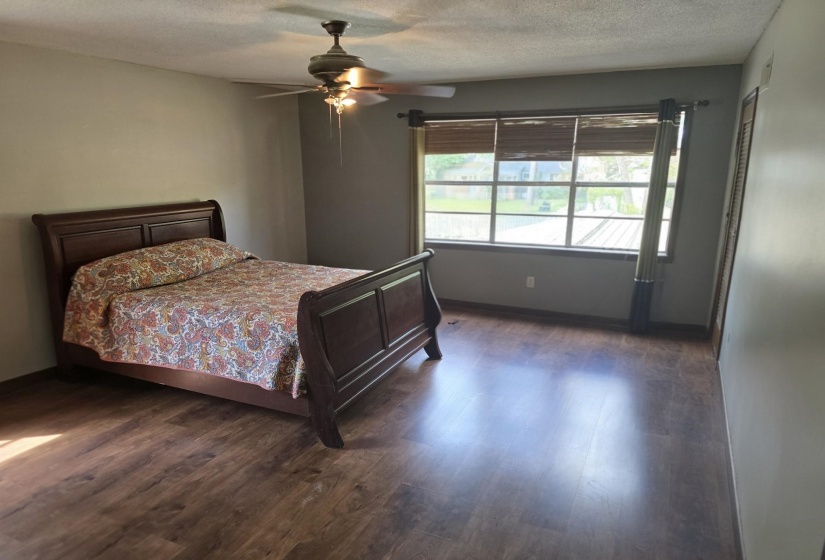 Bedroom with dark wood-style floors, a textured ceiling, and a ceiling fan