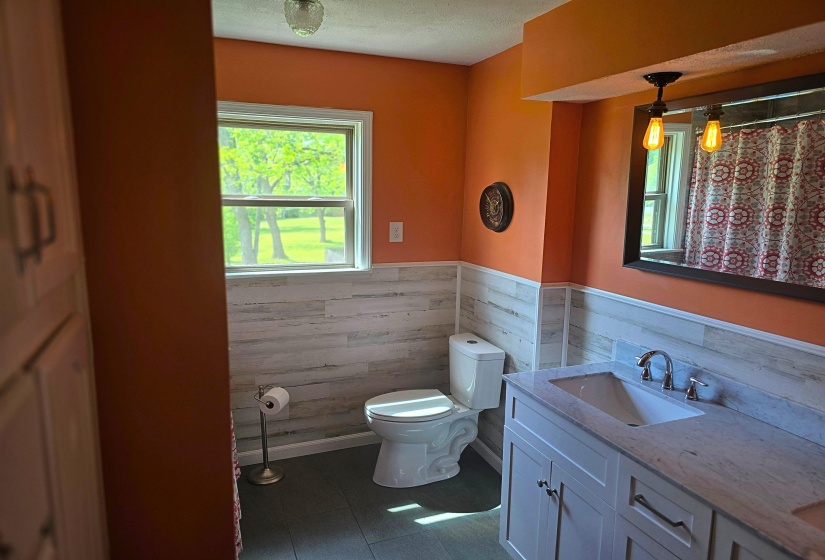 Bathroom with double vanity, wainscoting, and a shower with shower curtain