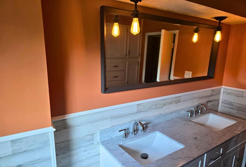 Bathroom with wainscoting, double vanity, and tile walls