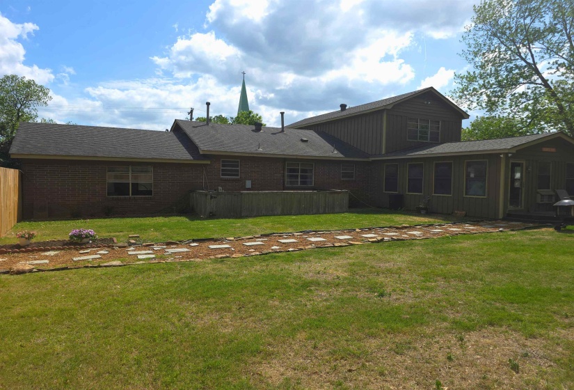 Back of property featuring brick siding, a yard, a patio, and a shingled roof