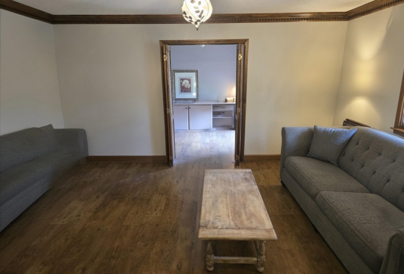 Living room with ornamental molding and dark wood-style floors