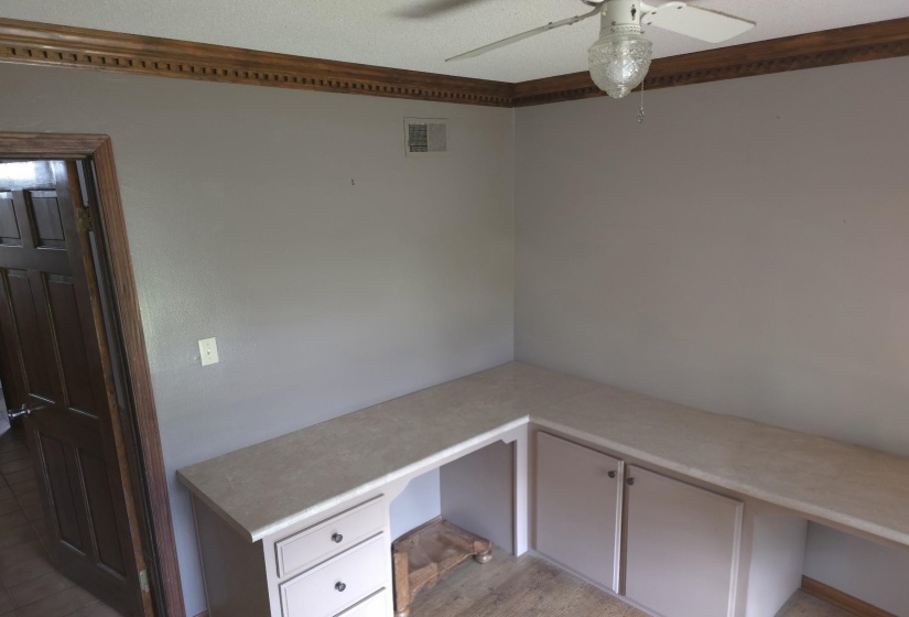 Unfurnished office with built in desk and ceiling fan