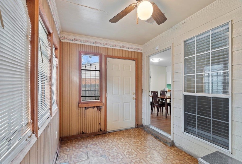 Entrance foyer featuring light flooring, ornamental molding, wood walls, and a ceiling fan