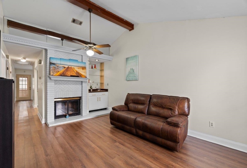 Living room featuring a fireplace, a ceiling fan, dark wood-style flooring, and built in shelves