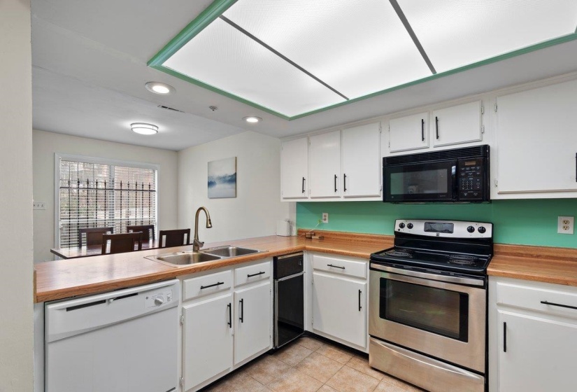 Kitchen featuring white cabinets, electric range, white dishwasher, recessed lighting, and light countertops