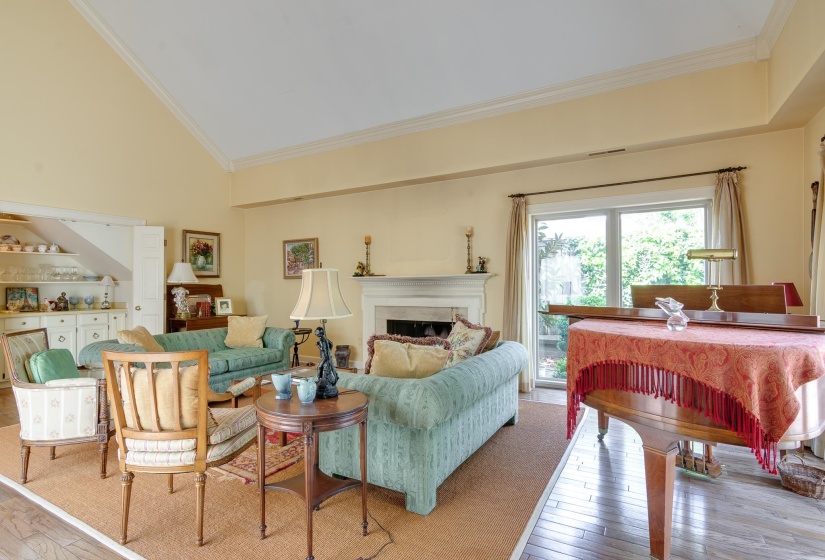 Living room with vaulted ceiling, light wood-style flooring, a fireplace, and ornamental molding