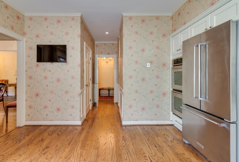 Kitchen featuring stainless steel appliances, light wood-style floors, crown molding, wallpapered walls, and white cabinetry
