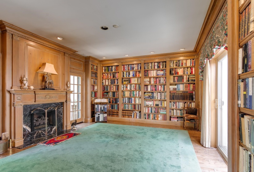 Living area with built in shelves, bookshelves, light wood-type flooring, a fireplace, and crown molding