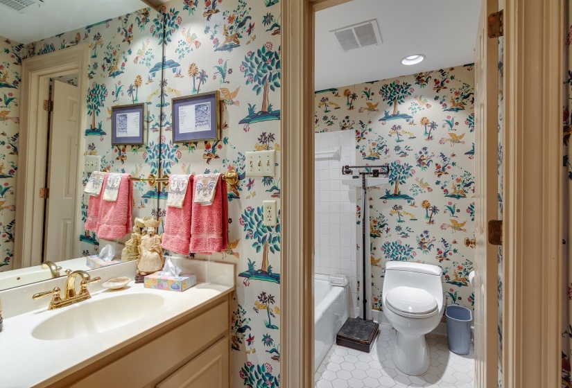Full bathroom with light tile patterned floors, vanity, wallpapered walls, and a bathtub