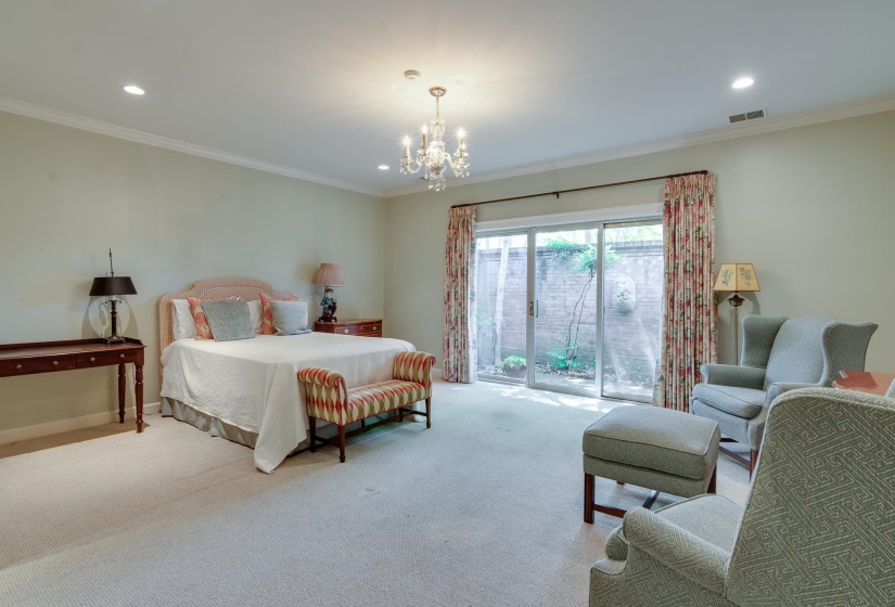 Carpeted bedroom featuring access to outside, ornamental molding, and a chandelier