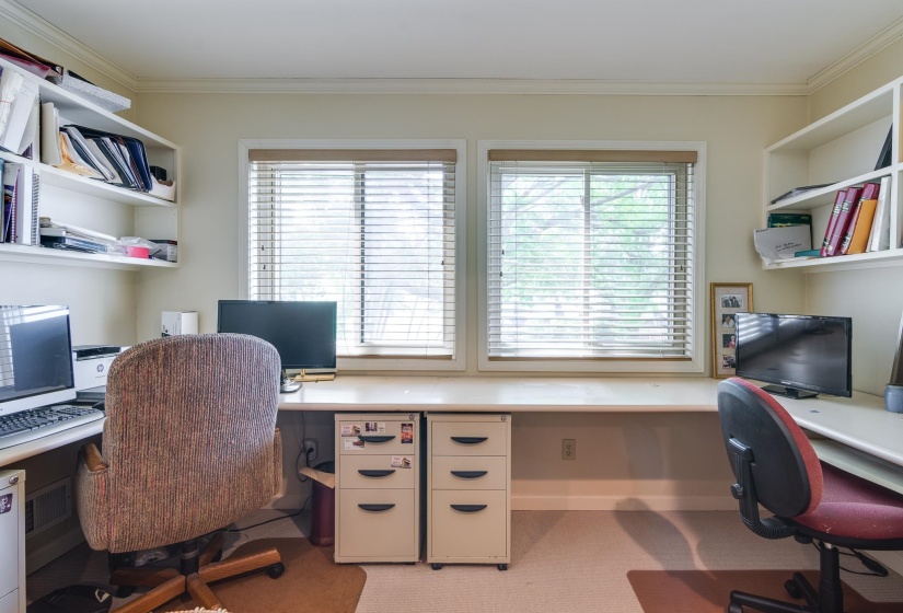 Office space featuring built in desk, ornamental molding, healthy amount of natural light, and light colored carpet