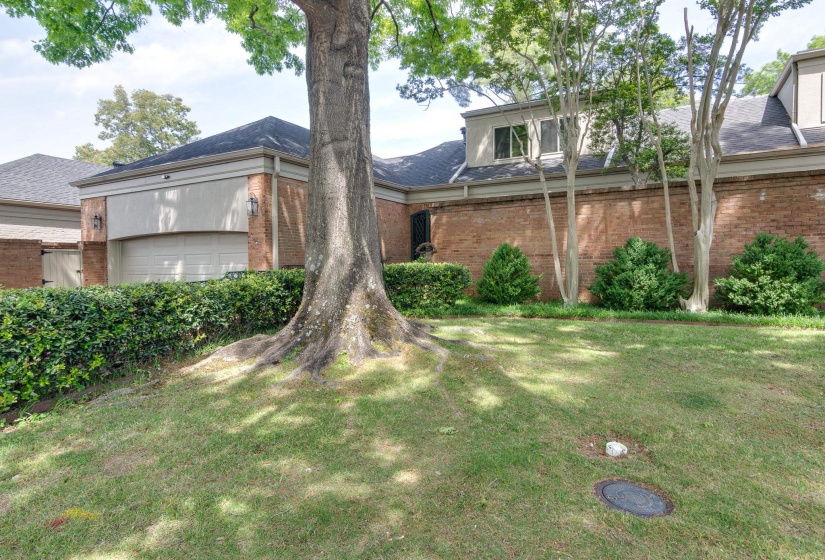 View of front of home with brick siding, a front yard, a shingled roof, and a garage