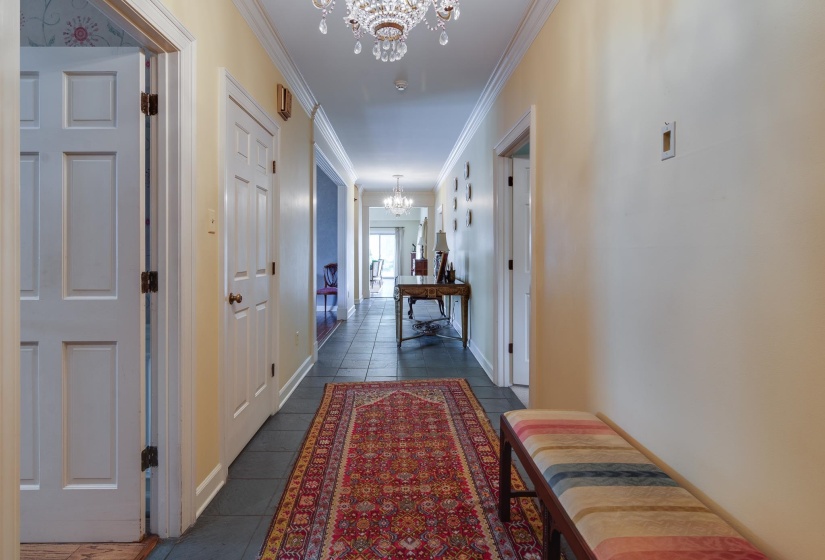 Hallway with a chandelier, crown molding, and dark tile patterned floors