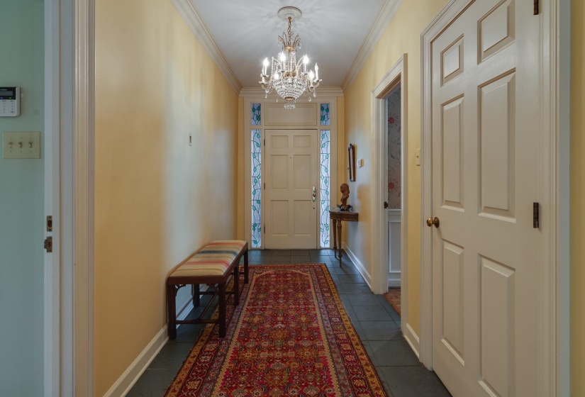 Foyer entrance featuring ornamental molding, hanging lights, and dark tile patterned floors