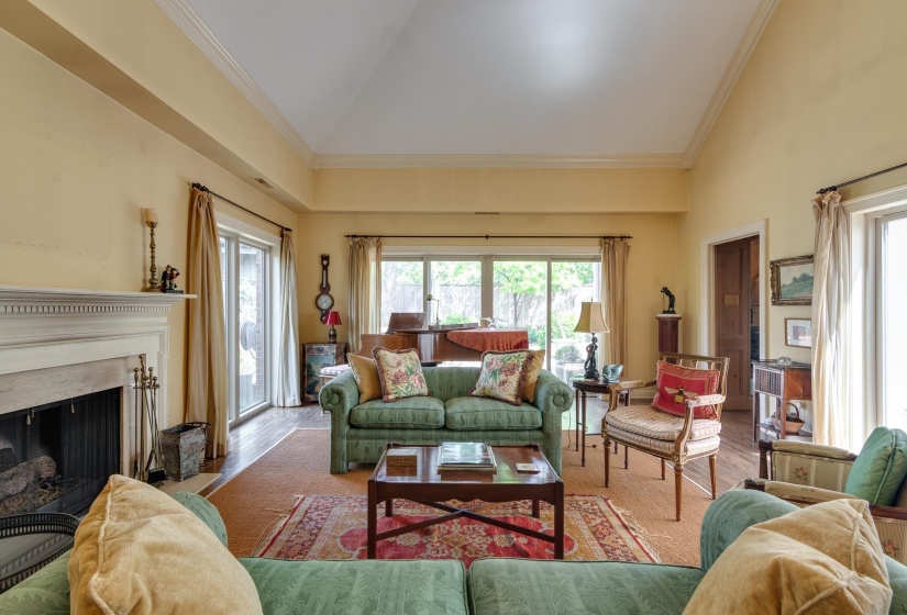 Living room featuring lofted ceiling, ornamental molding, a high end fireplace, and wood finished floors