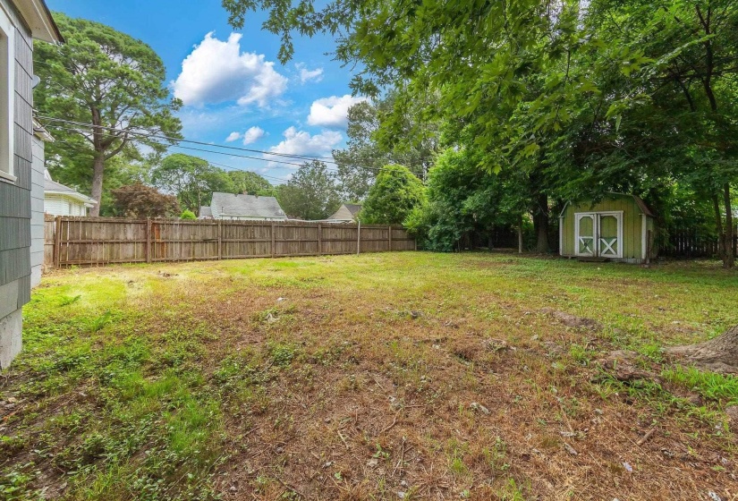 Fenced backyard featuring a storage unit