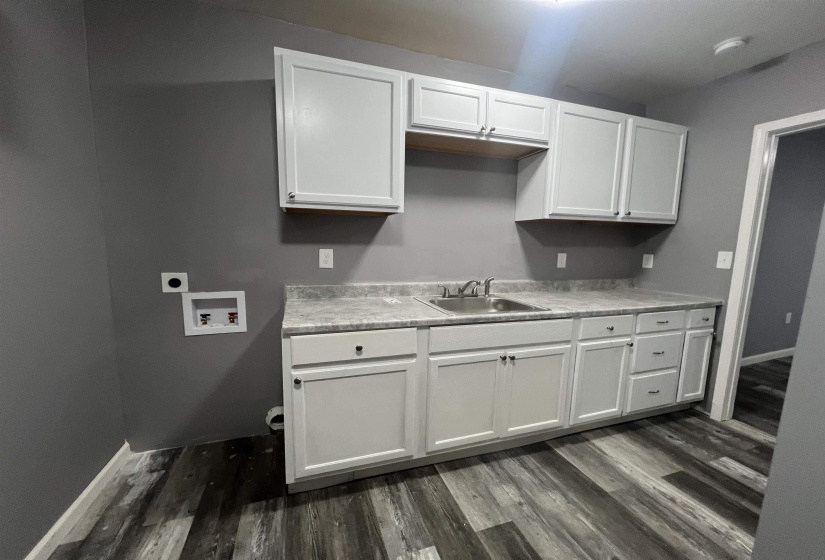 Kitchen featuring light countertops, white cabinets, and dark wood-style floors