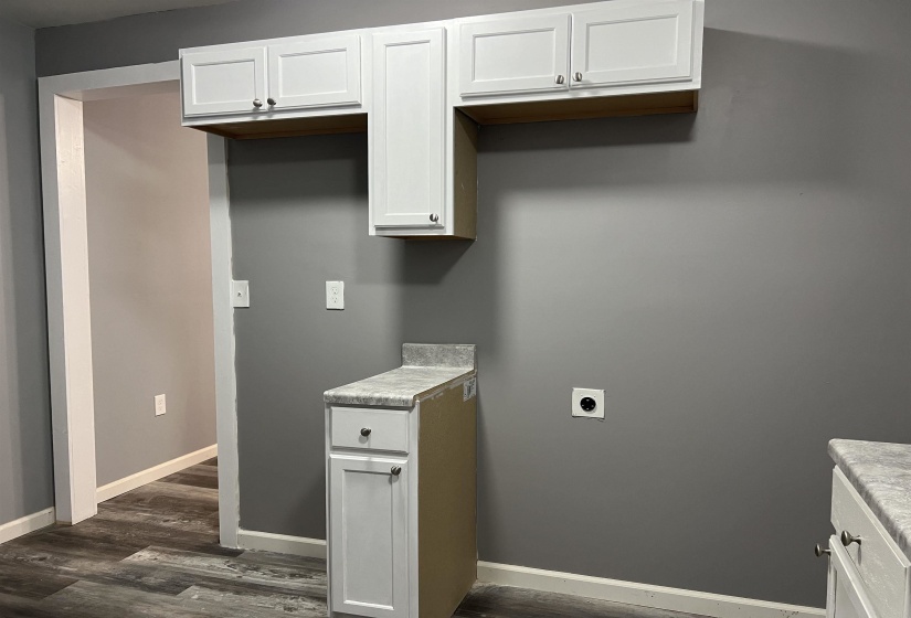 Laundry room featuring dark wood-style flooring, cabinet space, and electric dryer hookup