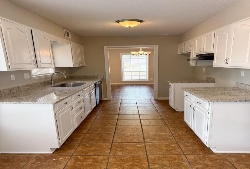 Kitchen with white cabinets, light tile patterned floors, and suspended lighting