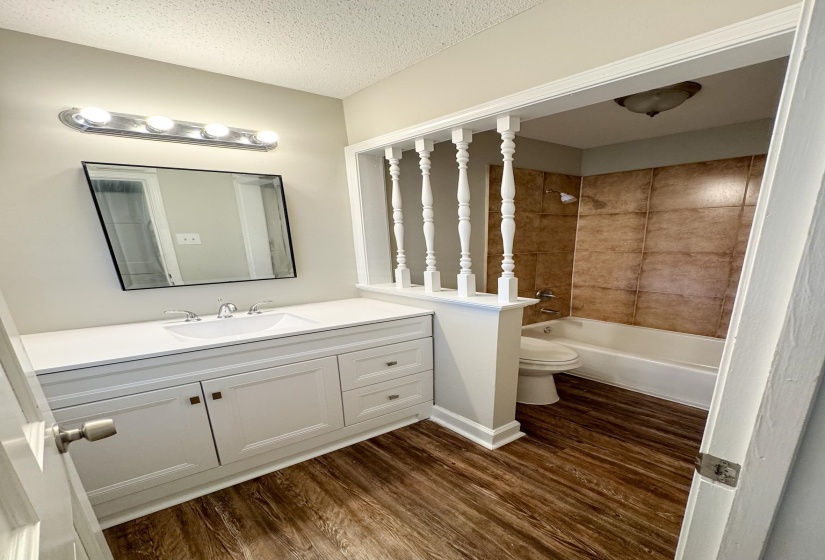 Bathroom featuring vanity, dark wood-style floors, shower / washtub combination, and a textured ceiling