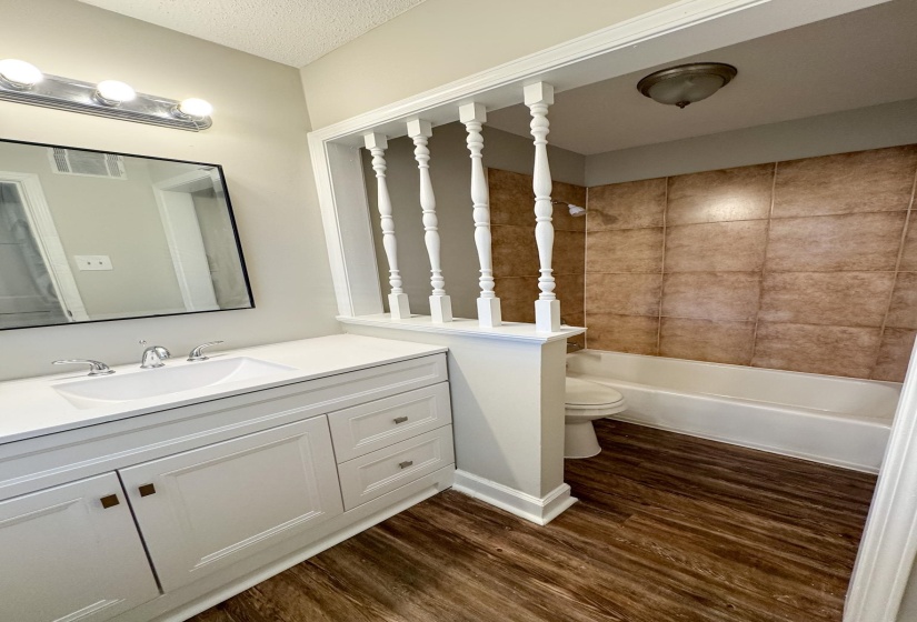 Full bath featuring vanity, washtub / shower combination, dark wood-type flooring, and a textured ceiling