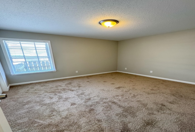Carpeted spare room with a textured ceiling and baseboards