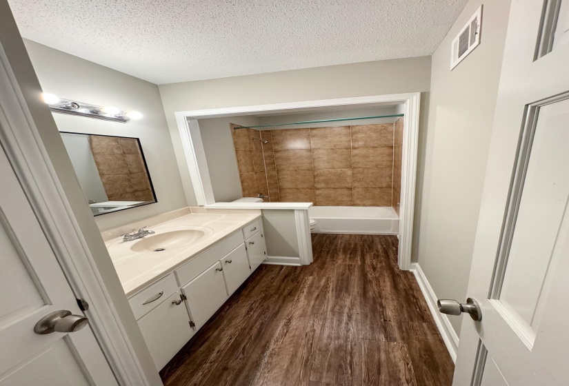 Full bath featuring vanity, dark wood-style floors, a textured ceiling, and shower / bathtub combination