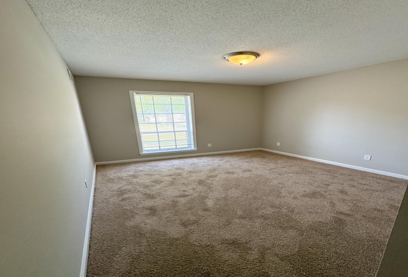 Carpeted spare room featuring a textured ceiling and baseboards