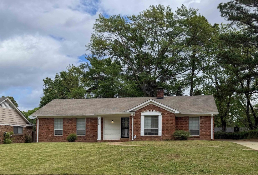 View of front of property with brick siding, a front yard, and a shingled roof