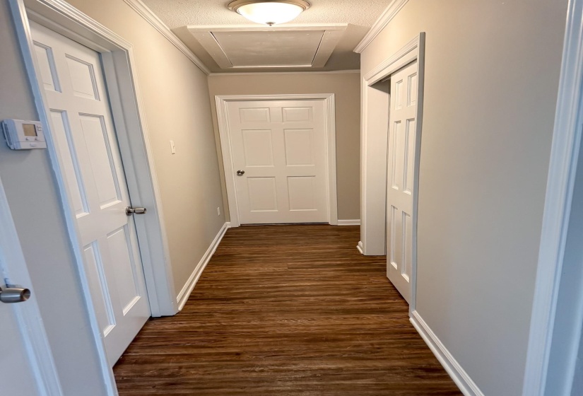 Hallway featuring dark wood-style flooring, a textured ceiling, and crown molding