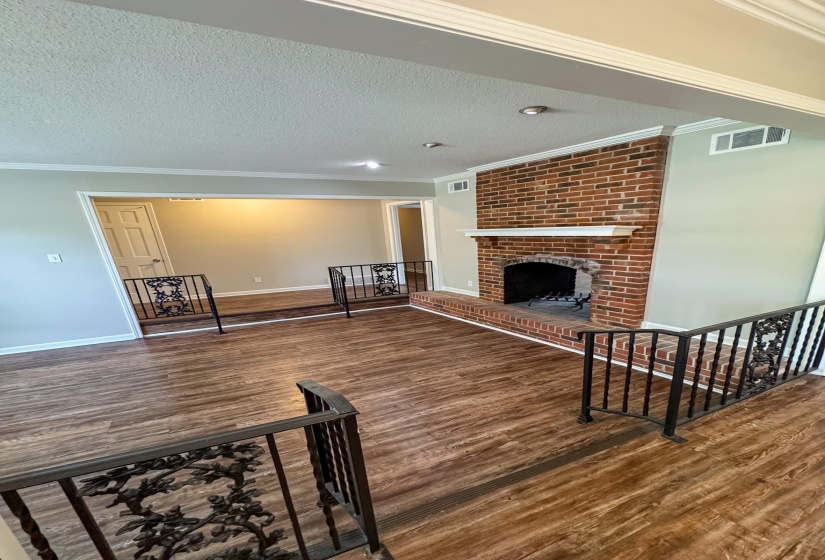 Living room featuring dark wood-type flooring, a fireplace, crown molding, and a textured ceiling