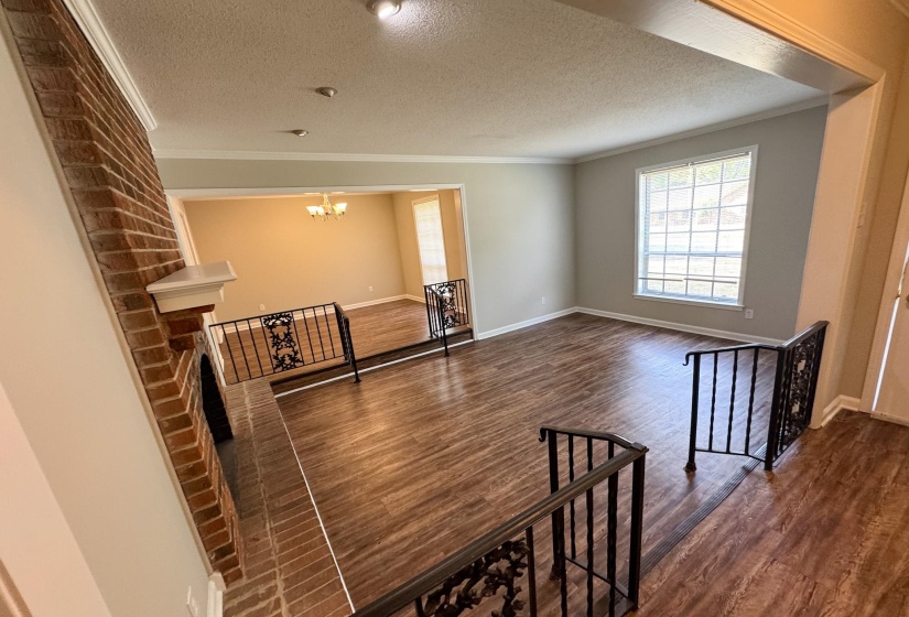 Hallway featuring dark wood finished floors, ornamental molding, an upstairs landing, a textured ceiling, and hanging lights
