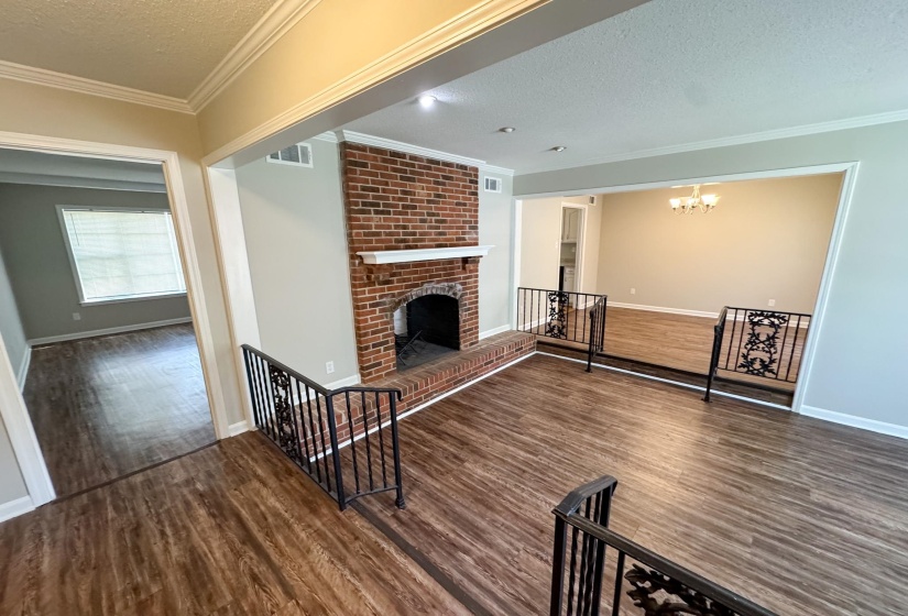 Unfurnished living room with a textured ceiling, a fireplace, crown molding, dark wood-style floors, and suspended lighting