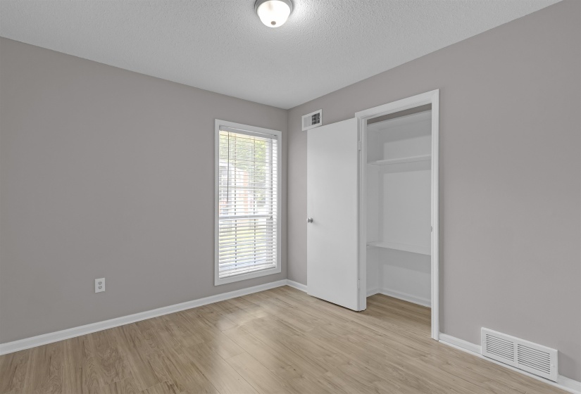 Unfurnished bedroom featuring light wood-type flooring, a textured ceiling, and a walk in closet
